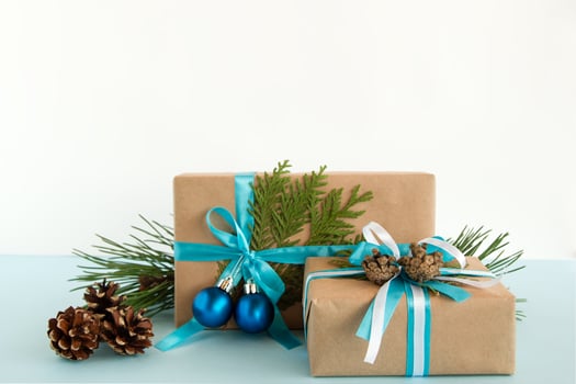 Christmas gift boxes wrapped of craft paper, blue and white ribbons, decorated of fir branches, pine cones and Christmas balls on the blue and white background. Copy space. photo