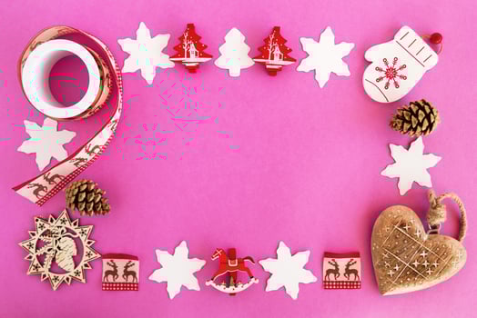 Top view on the frame from red and white wooden Christmas decorations and pine cones on the pink background with copy space. photo