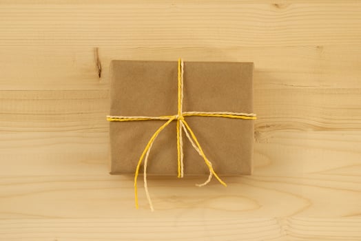 Gift box wrapped of craft paper and white and yellow ribbon on the wooden background, top view. photo
