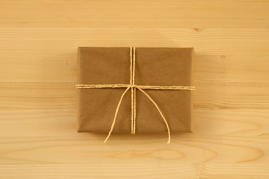 Gift box wrapped of craft paper and yellow ribbon on the wooden background, top view. photo