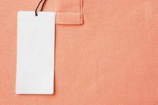 Blank white clothes tag label on pink fabric texture background photo
