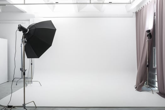 interior of bright space of photo studio with large white cyclorama with lighting equipment