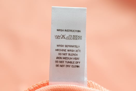 White laundry care washing instructions clothes label on pink cotton shirt photo