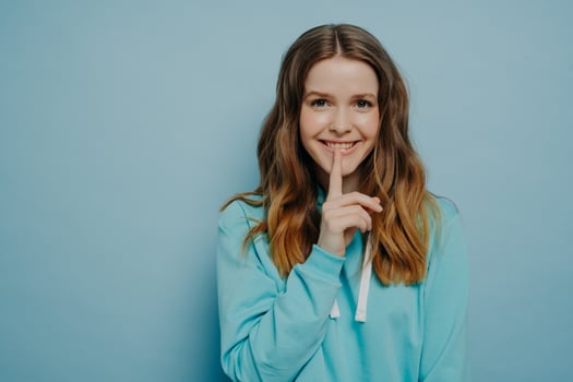Cute female teenager demonstrating shushing sign photo