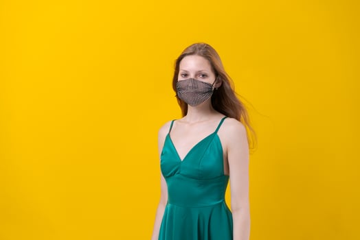 Woman in stylish outfit with designer protective face mask, green dress posing photo