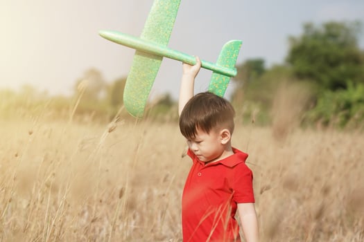 boy happy playing with toy plane in nature and clear morning sky, Child concept and dream plane to become pilot. want to fly like an airplane photo