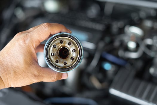 Close up hand a man hold old oil filter for car maintenance concept in engine room background photo