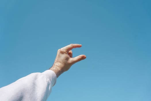 hand up in the air gesturing in the blue sky, blue background photo