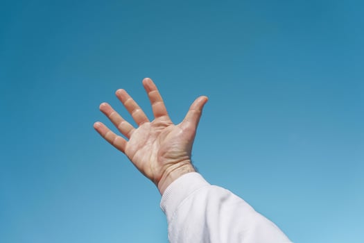 hand up in the air gesturing in the blue sky, blue background photo