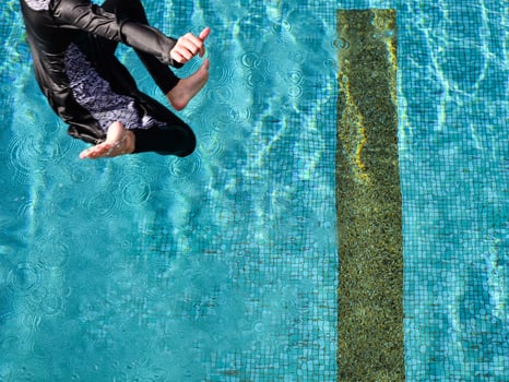 High level view a girl jumping into the pool in a sunny day photo