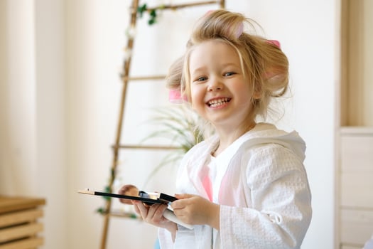 Happy little girl in curlers holding makeup , photo