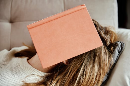Woman sleeps on couch with book photo