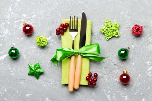 Top view of holiday set of fork and knife on cement background. Close up of Christmas decorations and toys. New Year Eve concept photo