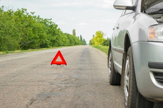 Red emergency stop sign and broken silver car on the road photo