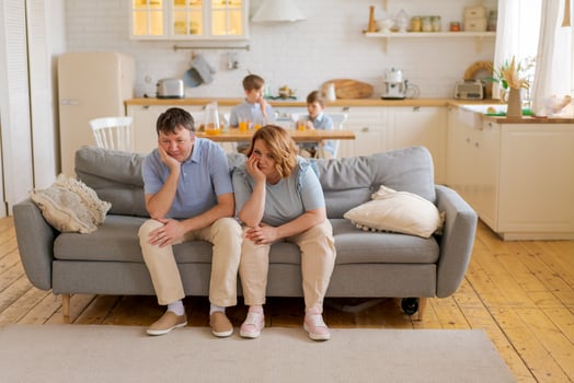 Tense parents sitting on sofa tired crazy loud hyperactive little kids photo