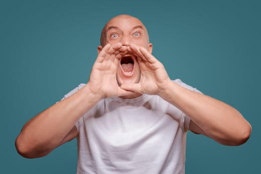 Handsome happy man wearing white T-shirt, guy speaking loudly, isolated on blue background photo