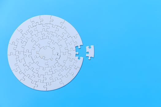White jigsaw puzzle on a blue background. Completing final task, missing jigsaw puzzle pieces and business concept with a puzzle piece missing. photo