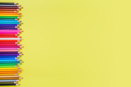 Many different colored pencils on a yellow background. Place your text. photo