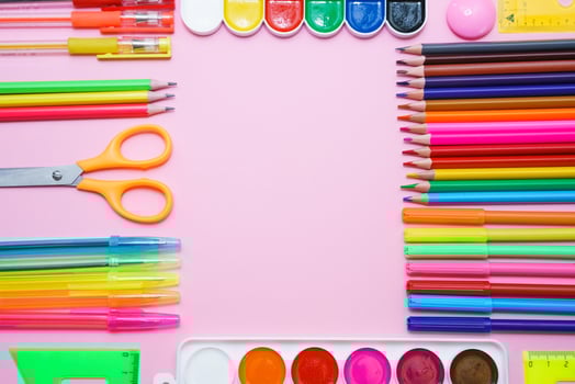 School stationery colorful paint pencils and pens on pink background in form photo