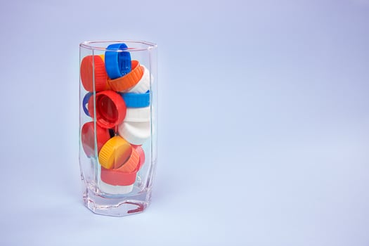 Waste multicolored plastic lids in a water glass photo