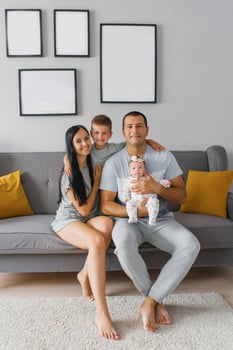 Happy family with two children are sitting on the sofa in their house and smiling photo
