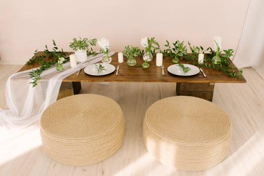 Coffee table in boho or rustic style, decorated and served for a holiday or dinner and ottomans covered with rope in the living room in the interior photo