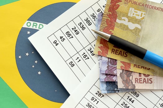 Pen with Brazilian money bills on blank of lottery game. Concept of luck and gambling in Brazil photo