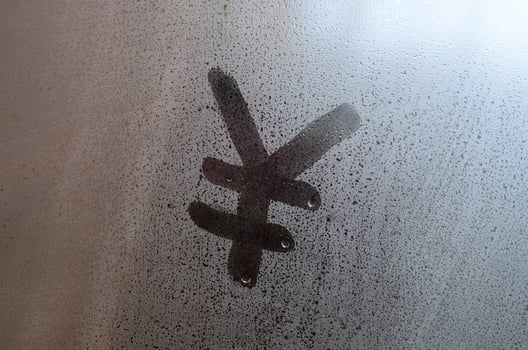 Chinese Yen Symbol is written with a finger on the surface of the misted glass photo
