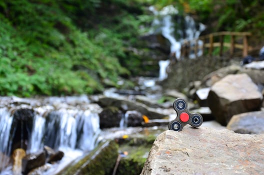 The wooden spinner lies on the rocks against the background of a small waterfall and a river photo