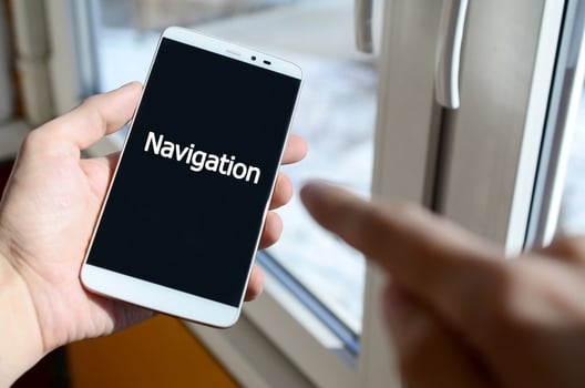 A person sees a white inscription on a black smartphone display that holds in his hand. Navigation photo