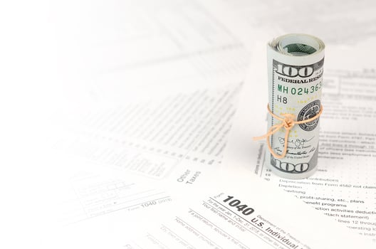 1040 Individual income tax return form with roll of american dollar banknotes photo