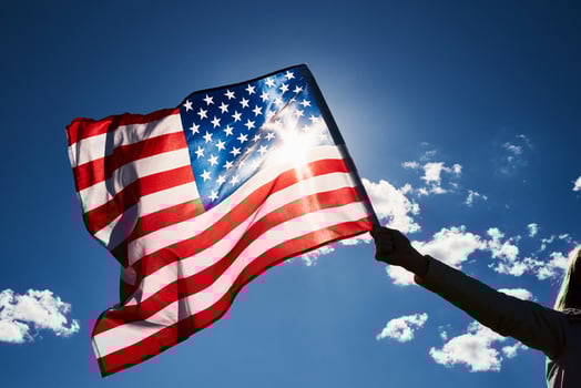 Waving usa flag in hand against blue sky photo