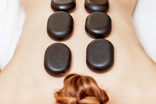 Black hot stones lying on female back photo