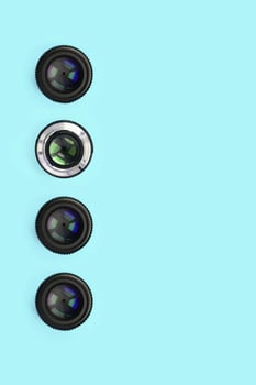 A few camera lenses with a closed aperture lie on texture background of fashion pastel blue color paper photo