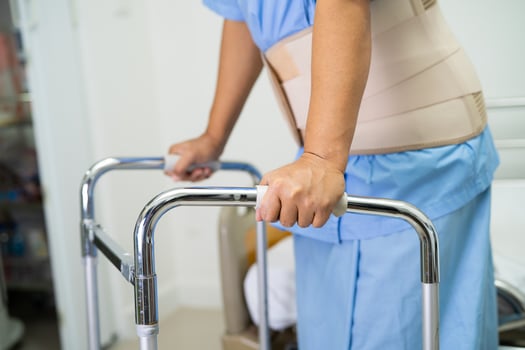 Asian lady patient wearing back pain support belt for orthopedic lumbar with walker. photo