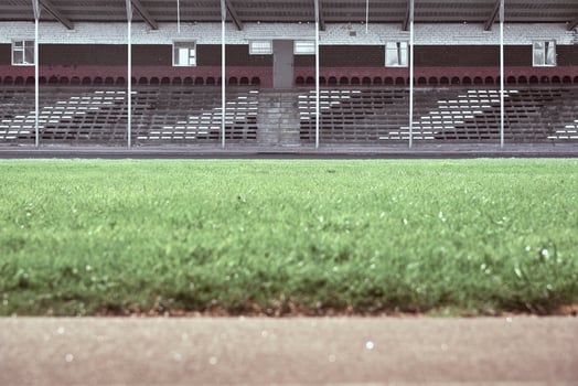 Empty audience seats at the stadium. In the foreground is a green field in blur. photo