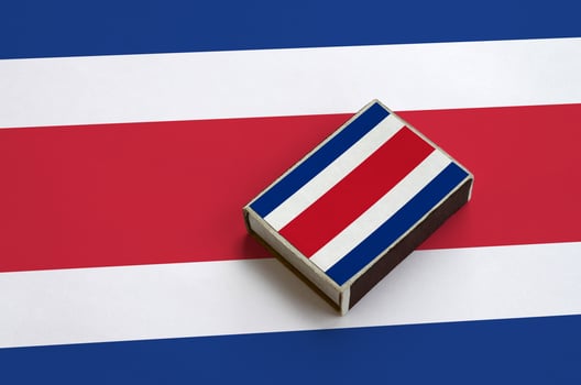Costa Rica flag  is pictured on a matchbox that lies on a large flag photo