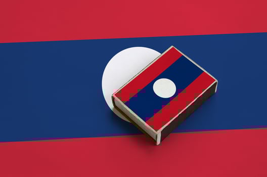 Laos flag  is pictured on a matchbox that lies on a large flag photo