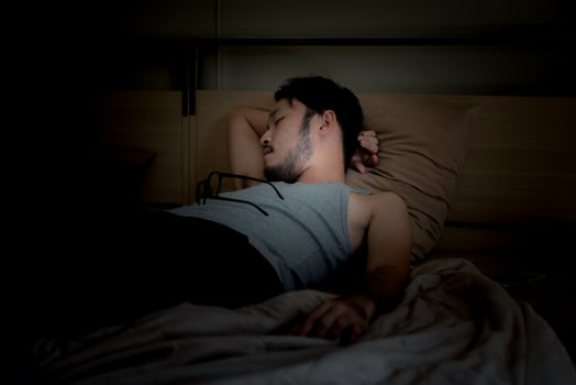 Handsome Young Man Sleeping Cozily on a Bed in His Bedroom at Night. photo