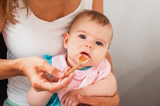 Mother feeding cute baby girl vegetable puree from a spoon. Healthy eating nutrition for little kids photo