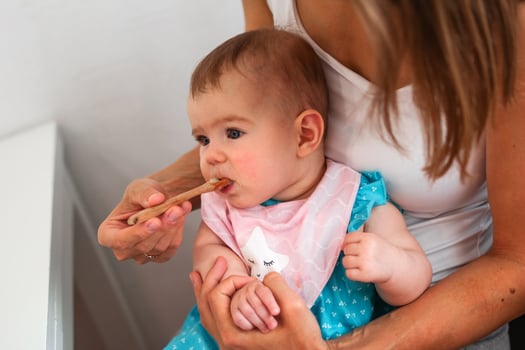 Mother feeding cute baby girl vegetable puree from a spoon. Healthy eating nutrition for little kids photo