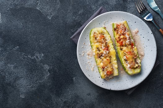 Baked stuffed zucchini boats with minced chicken mushrooms and vegetables with cheese on a plate. Copy space photo