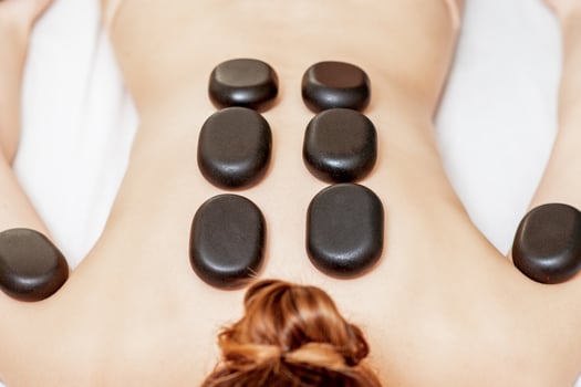 Black hot stones lying on female back photo