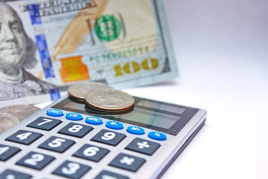 Calculator and dollar bills are placed on a white table. photo