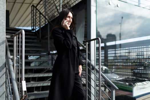 young ambitious woman head speaks on a mobile phone well against the backdrop of a strong office building photo