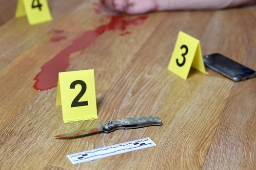 Crime scene investigation - Bloody knife and victims hand with yellow criminal markers on kitchen floor photo