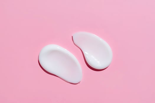 Smears of cosmetic cream or lotion on pink background. smear smudge stroke on color background. Creamy beauty product closeup photo
