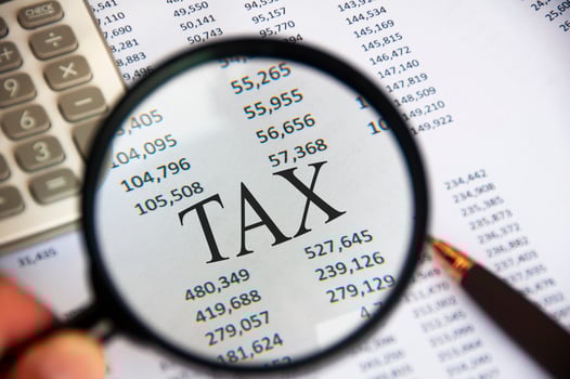 Magnifying glass focusing on TAX word on analysis paper. Tax concept photo