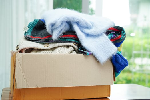 Clothes donations in cardboard box for volunteer. photo