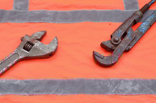 Adjustable and pipe wrenches against the background of an orange signal worker shirt photo